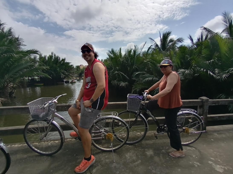 Deux personnes à vélo sur un pont entouré d'une végétation luxuriante.