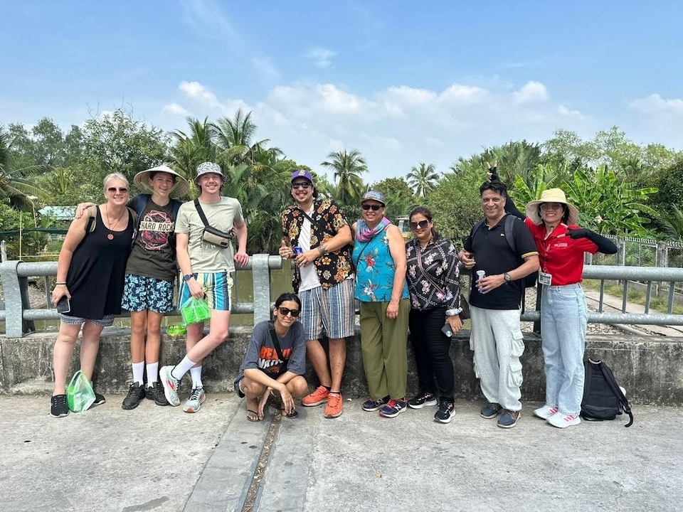Un groupe de personnes posant sur un pont avec des arbres en arrière-plan.