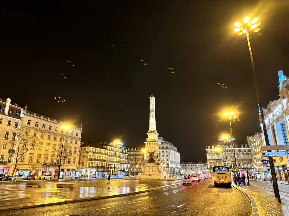 Place de la ville et monument illuminés la nuit.