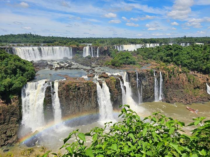 Sweeping view of multiple waterfalls with rainbow.