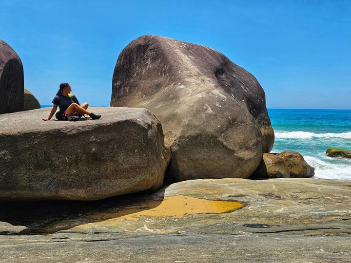 Person sitting on large rocks by the ocean.