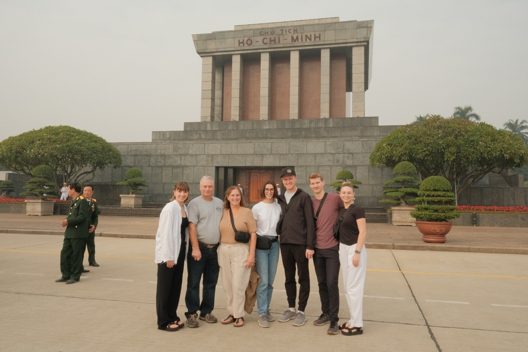 Un groupe de personnes debout devant le mausolée de Hô Chi Minh.