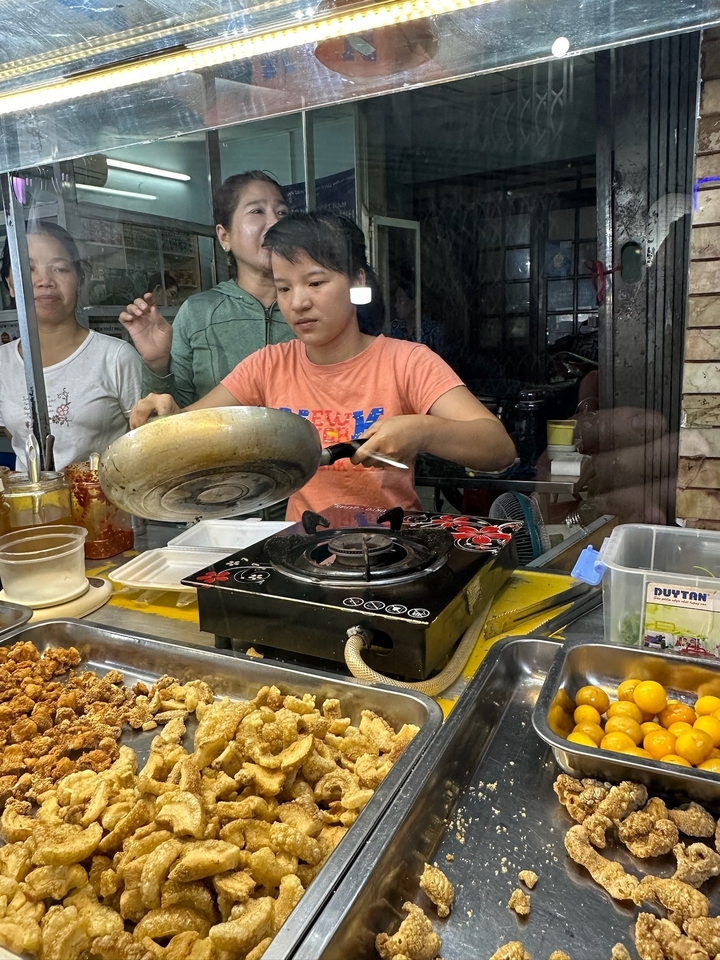 Vendeur de nourriture de rue cuisinant avec une poêle.