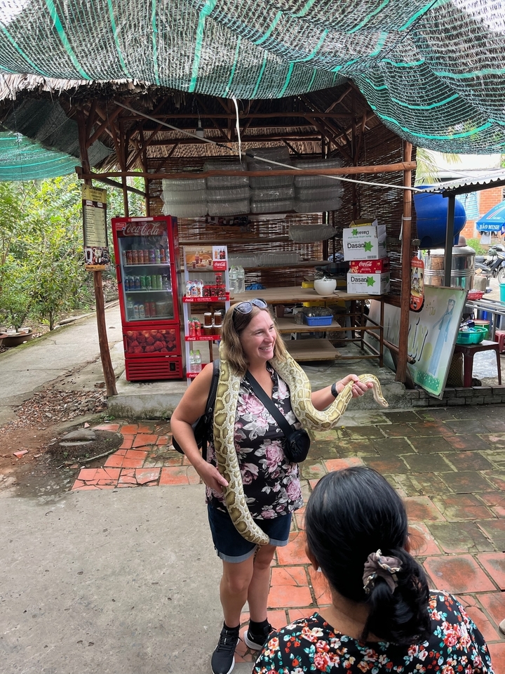 Une femme tenant un serpent dans une petite zone de marché.