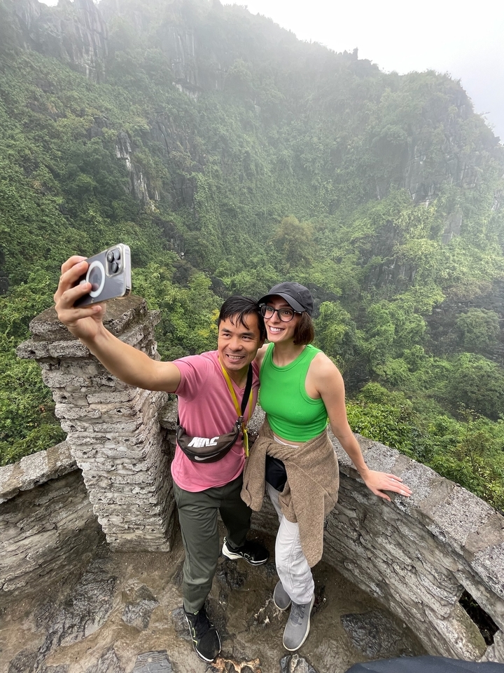 Un couple qui prend un selfie avec des collines pittoresques en arrière-plan.