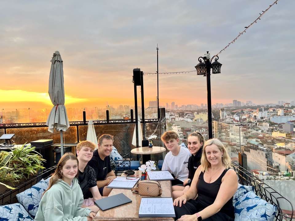 Groupe de personnes dînant sur un toit pendant le coucher du soleil.