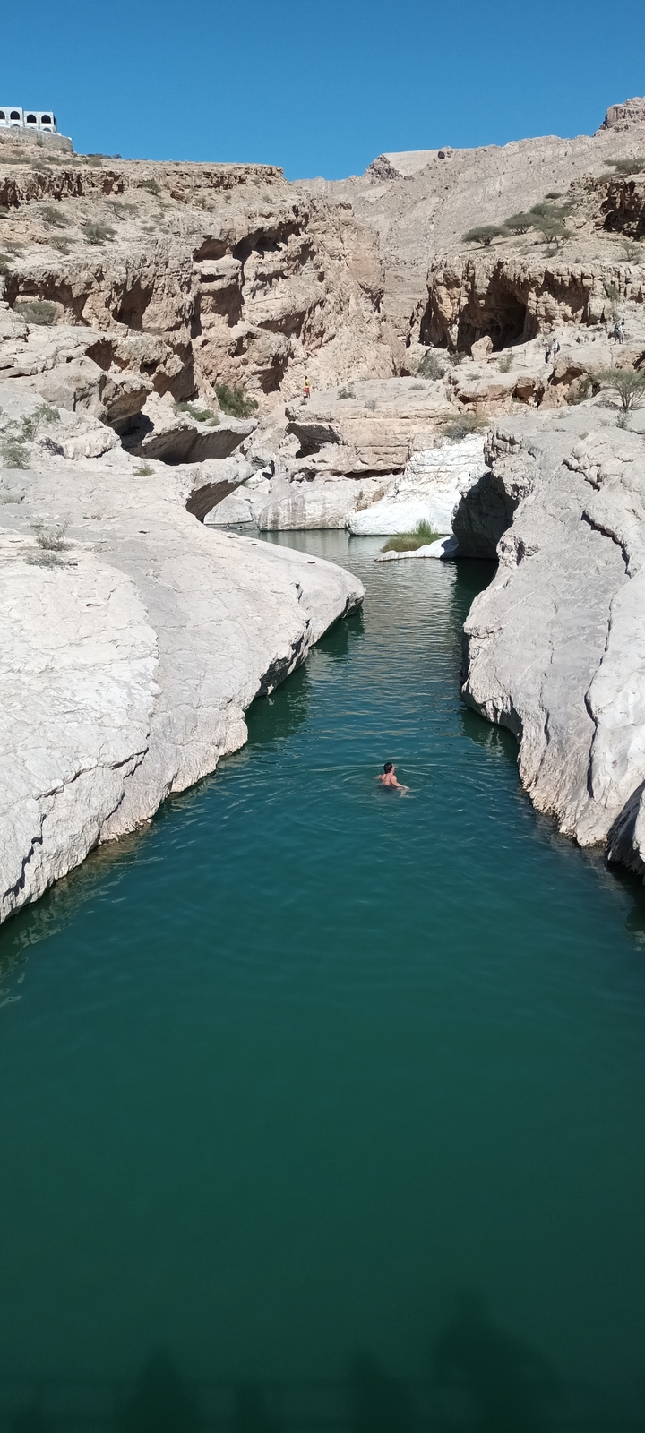 Personne nageant dans un bassin d'eau naturel entouré de rochers.