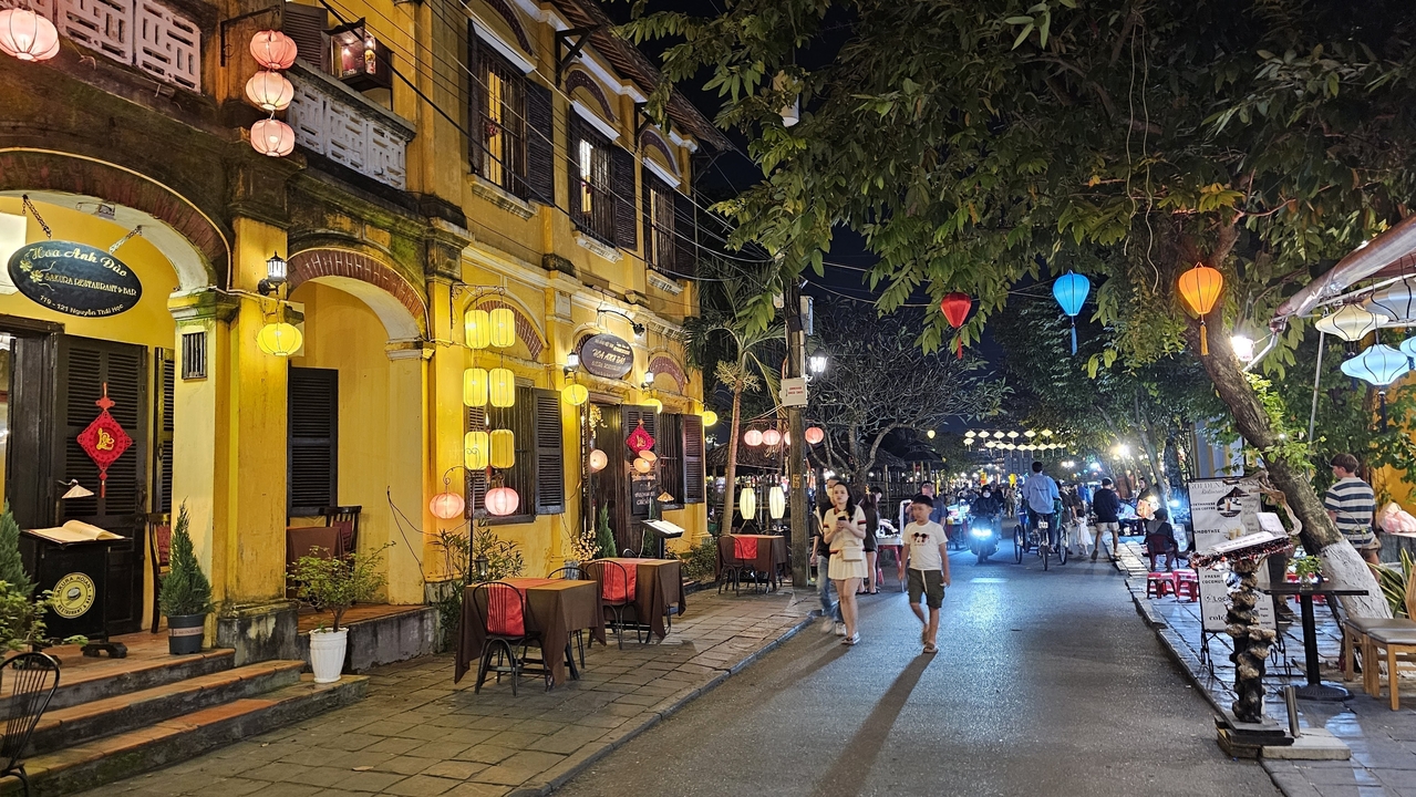 Scène de rue à Hoi An avec des lanternes colorées et des devantures de magasins.