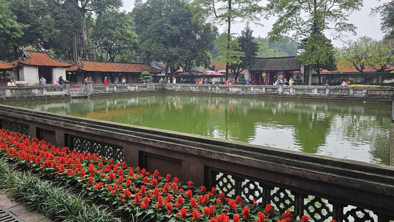 Temple de la Littérature à Hanoï avec un bassin réfléchissant et des personnes.