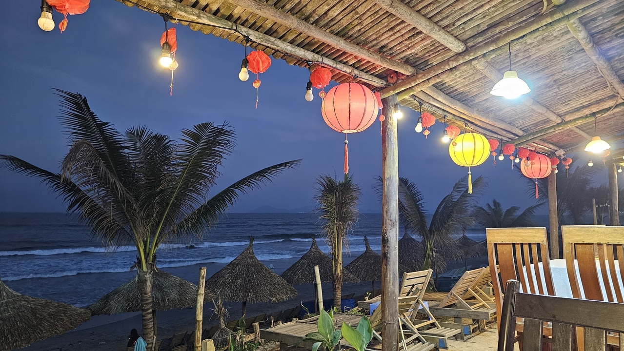 Espace de restauration en plein air avec vue sur l'océan et lanternes.