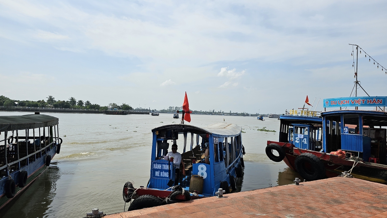 Bateaux amarrés dans le delta du Mékong avec vue sur la rivière et le ciel dégagé.
