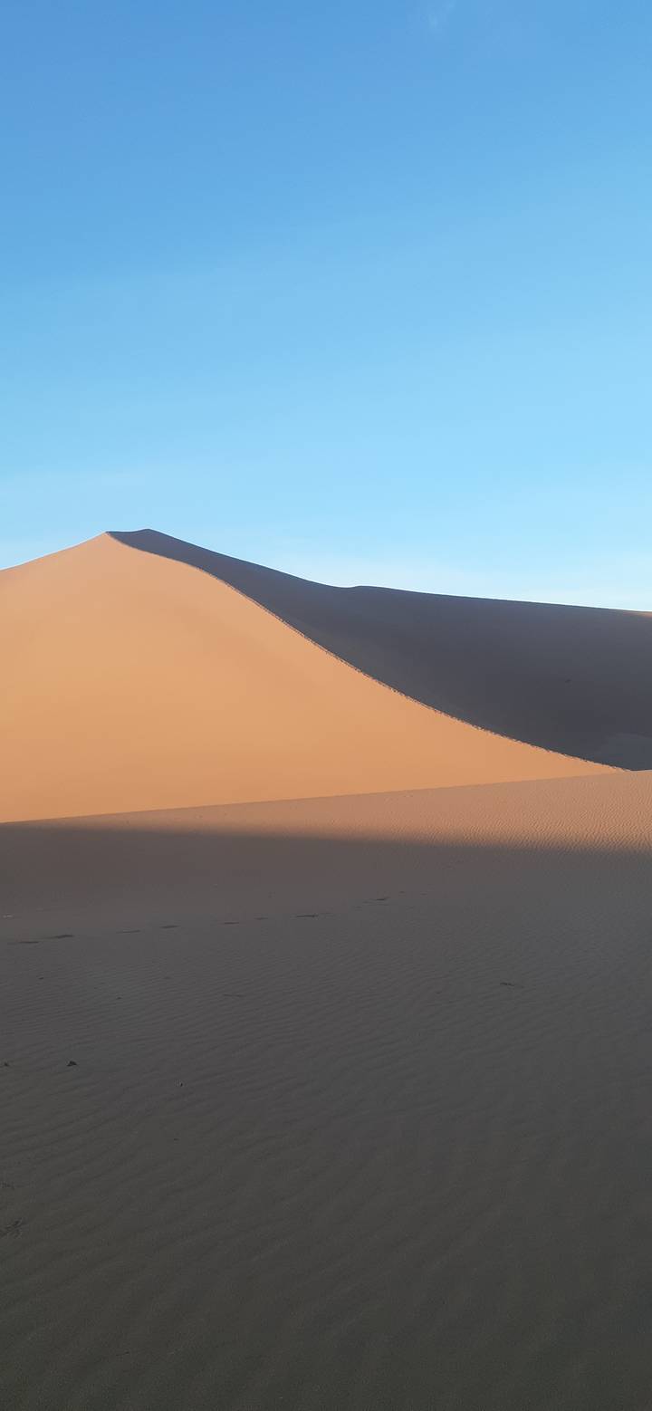 Dune de sable contre un ciel bleu clair.
