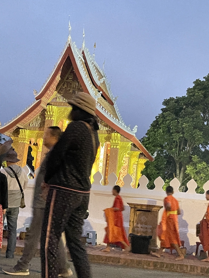 Groupe de personnes marchant près d'un temple vivement éclairé la nuit.