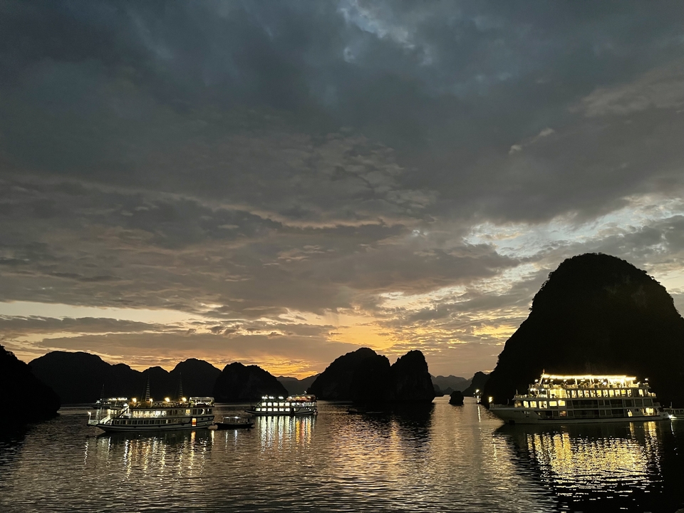 Silhouette de bateaux contre un coucher de soleil sur la baie d'Halong.