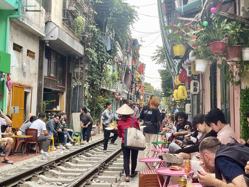 Rue animée avec des magasins et des gens près des voies ferrées.