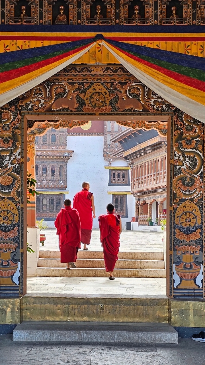 Des moines marchant dans une cour d'architecture traditionnelle.