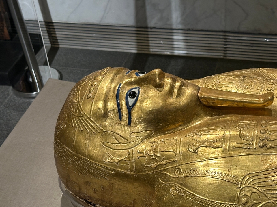 Sarcophage doré avec des motifs complexes dans un cadre muséal.