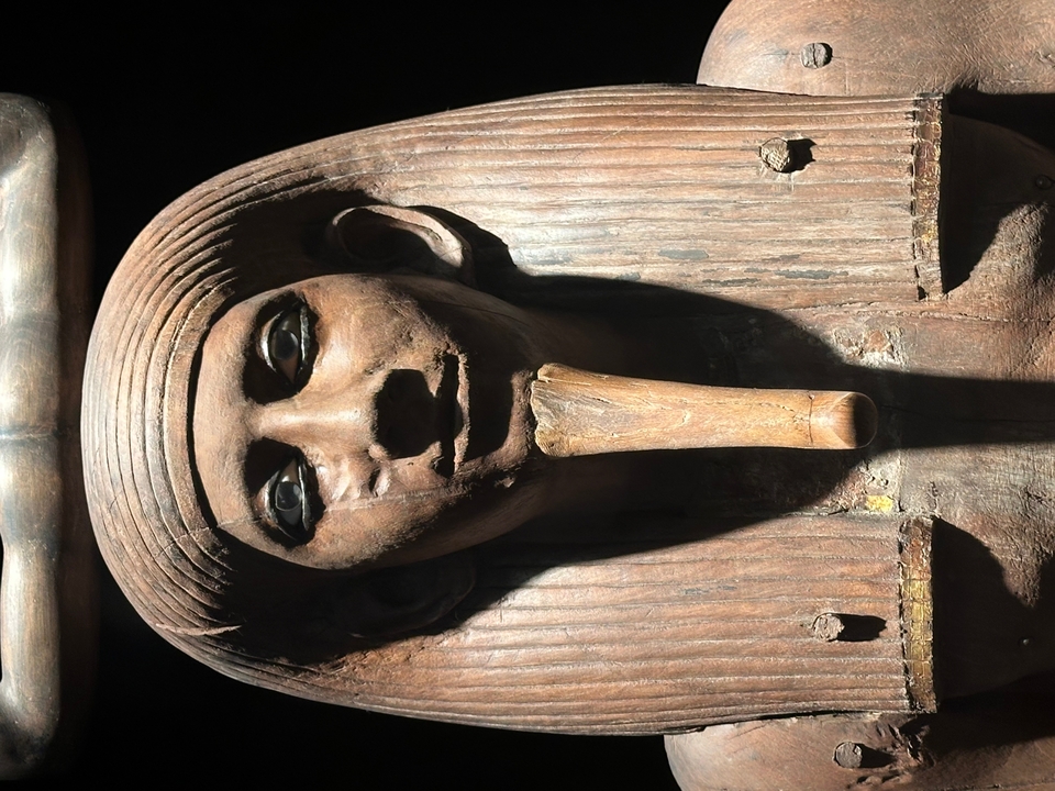 Sarcophage en bois avec des sculptures complexes dans un éclairage tamisé.