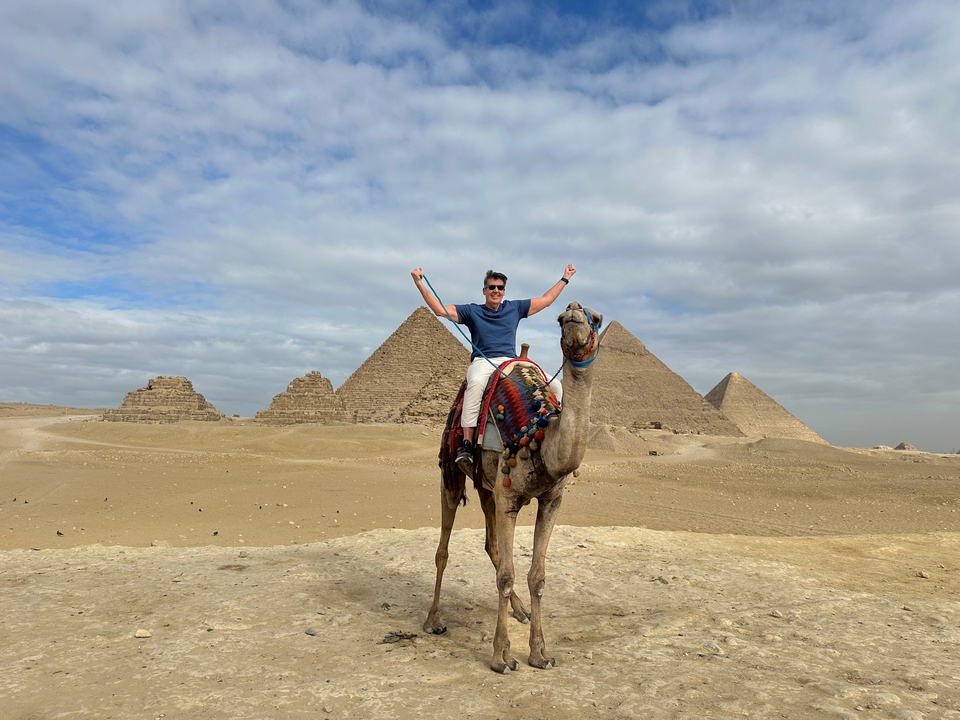 Homme sur un chameau devant les pyramides égyptiennes.