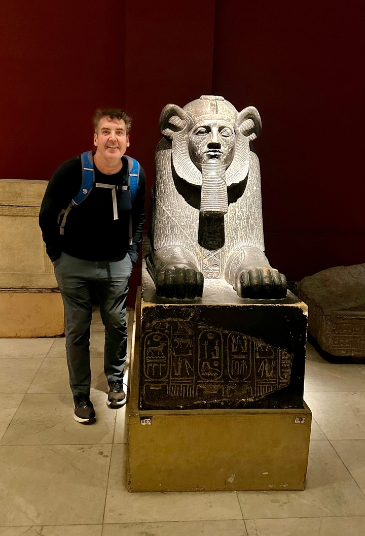 Personne posant avec une figure de pierre sculptée de manière ornée à l'intérieur.