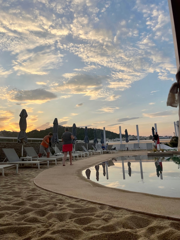 Des gens profitant de la détente au bord de la piscine au coucher du soleil.