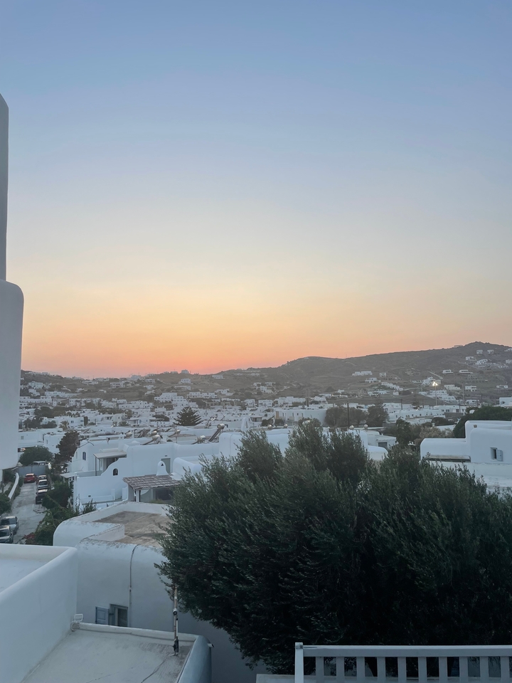 Vue de bâtiments blancs au coucher du soleil sur une colline.