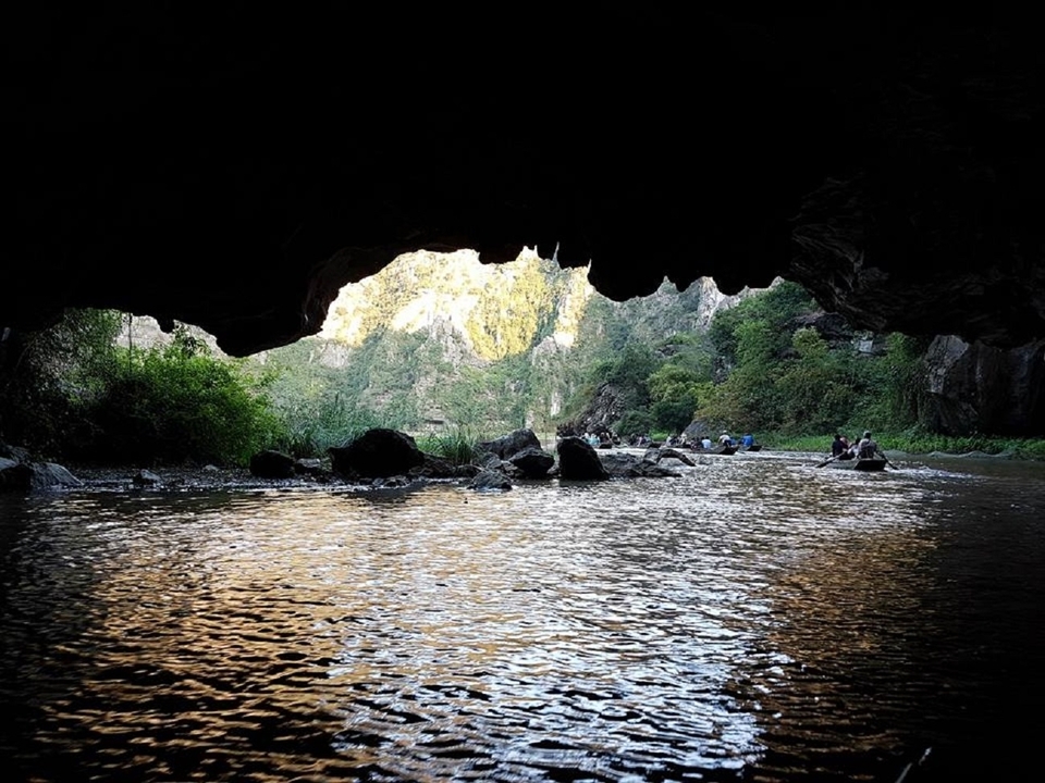 Rivière coulant à travers une grotte avec la lumière du soleil illuminant la sortie.