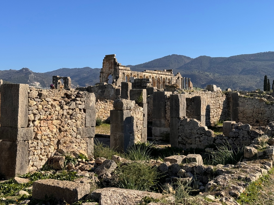Ruines de colonnes antiques se détachant sur un arrière-plan montagneux.