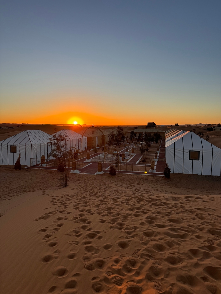 Un camping dans le désert avec des tentes au coucher du soleil.