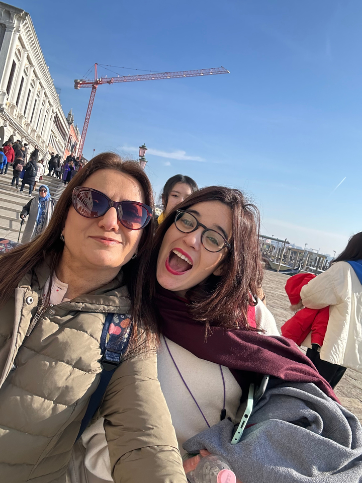 Deux femmes souriantes prenant un selfie avec un paysage urbain pittoresque en arrière-plan.
