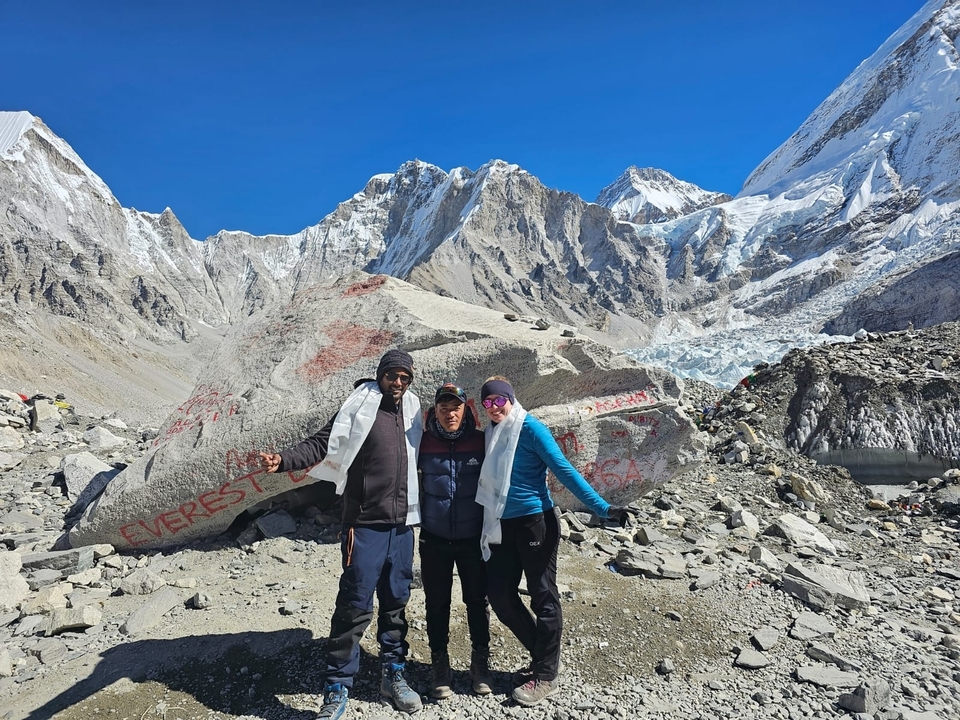 Trois personnes posant devant un terrain montagneux avec des sommets enneigés.