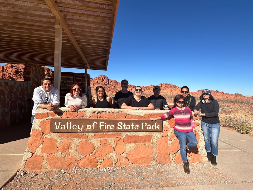 Groupe posant au Valley of Fire State Park avec des formations rocheuses rouges.