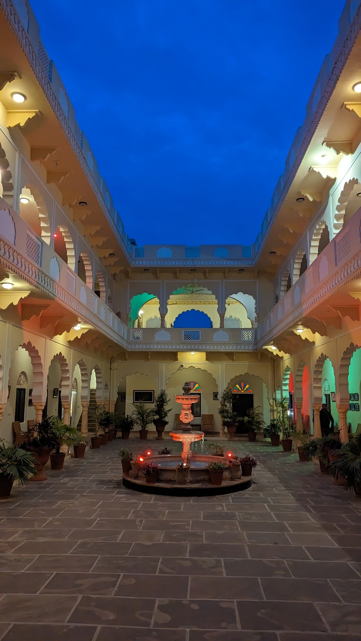Cour colorée éclairée la nuit avec des arches.