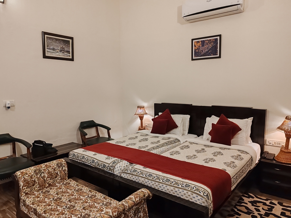 Intérieur d'une chambre d'hôtel avec un lit double, des chaises et des lampes décoratives.