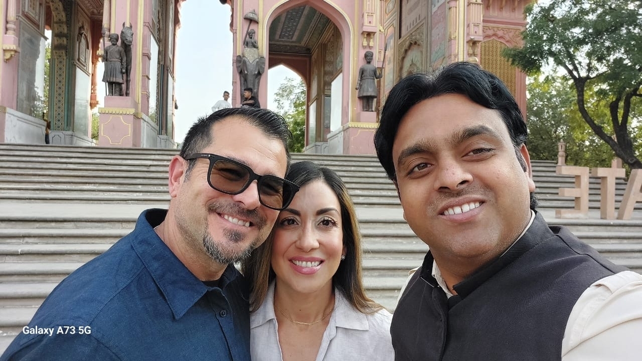 Deux hommes et une femme prenant un selfie avec un décor historique en arrière-plan.
