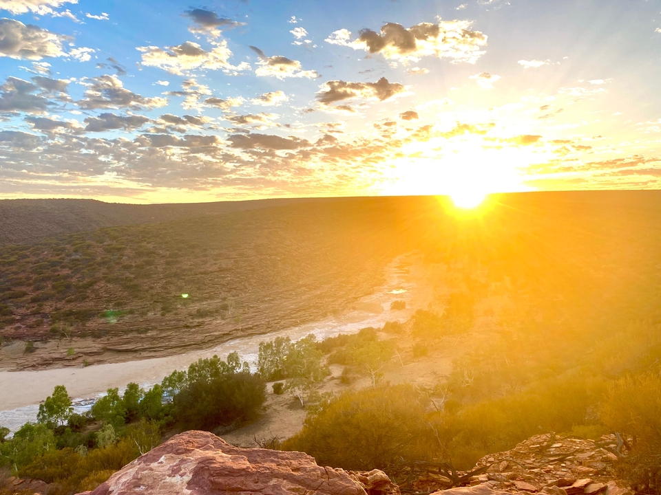 Vue du coucher de soleil sur un canyon avec une rivière et une végétation luxuriante.