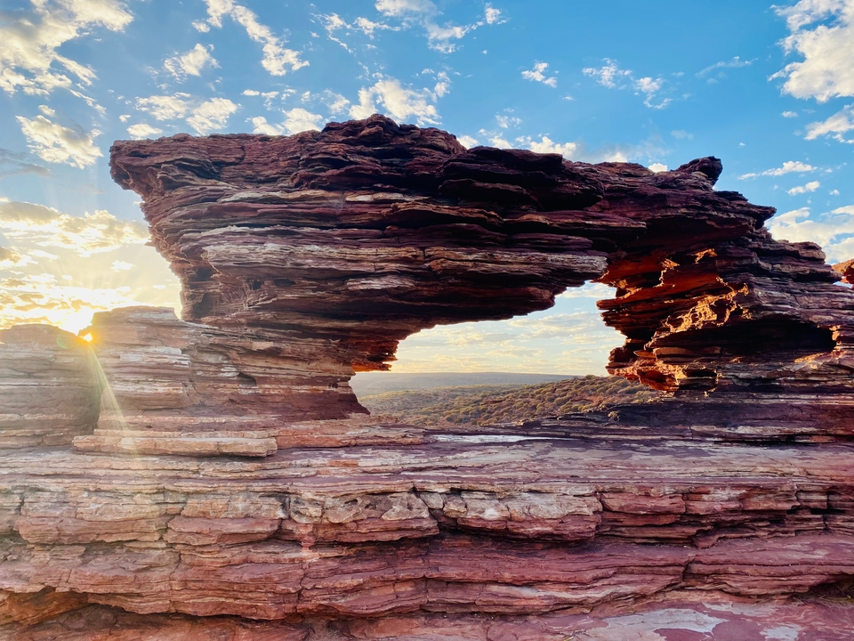 Formations rocheuses avec une arche naturelle au coucher du soleil.