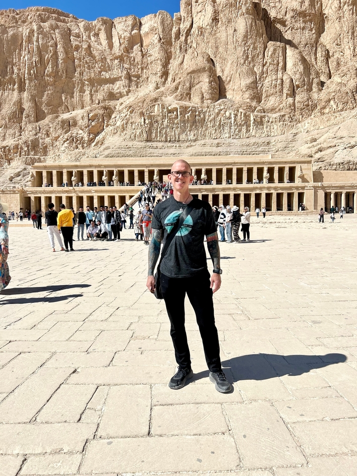Personne posant devant un grand temple avec des touristes.