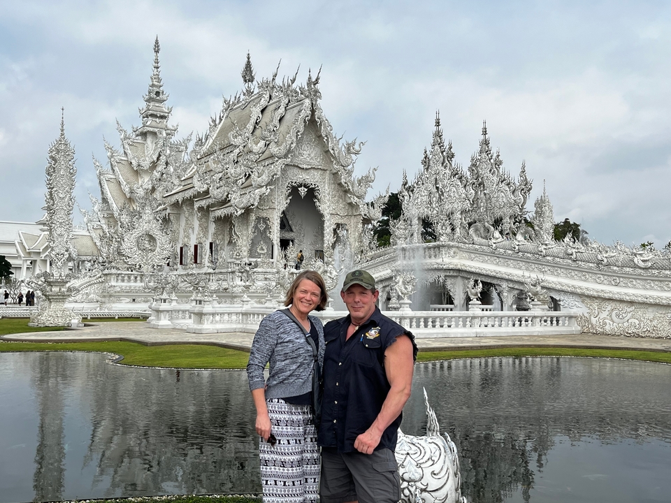 Couple debout devant un temple blanc orné.