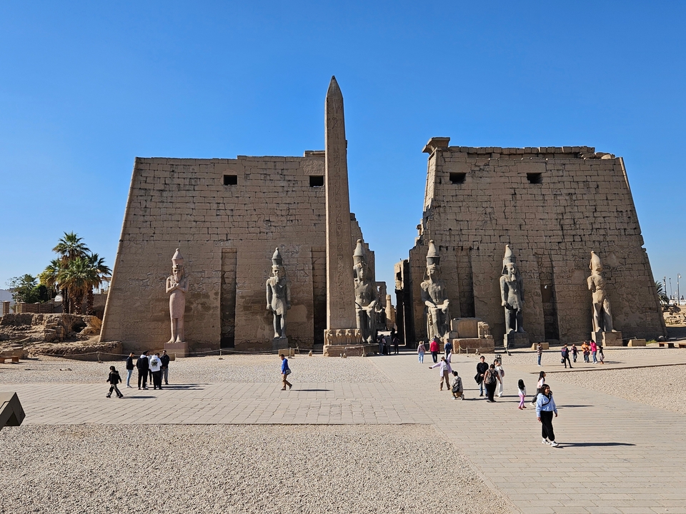 Des touristes explorant un complexe de temples anciens avec de grandes statues.