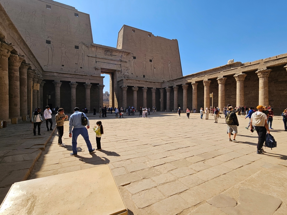 Zone de cour historique avec colonnes et touristes.