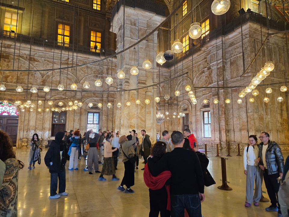 Vue intérieure d'une salle ornée avec de nombreuses lumières et des gens.