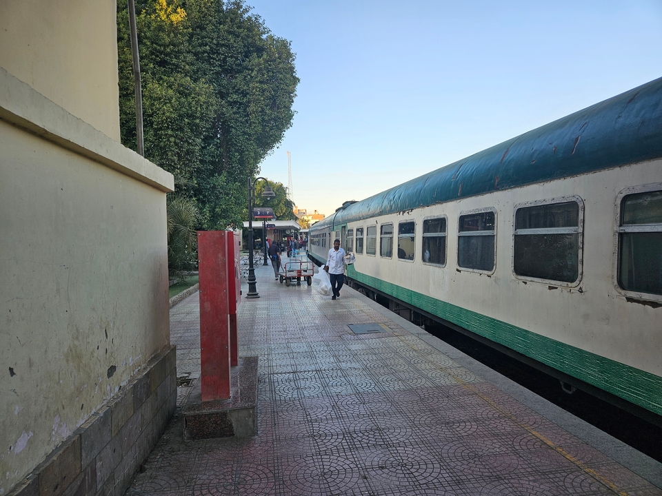 Des gens à une gare avec un train vintage vert.