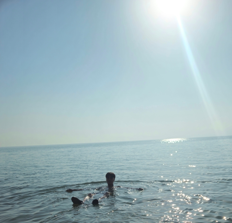 Personne assise sur le rivage d'une grande étendue d'eau bleue pendant une journée ensoleillée.