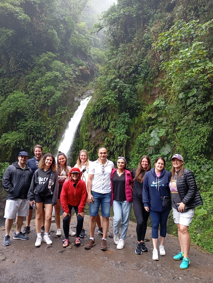 Groupe de personnes posant devant une cascade.