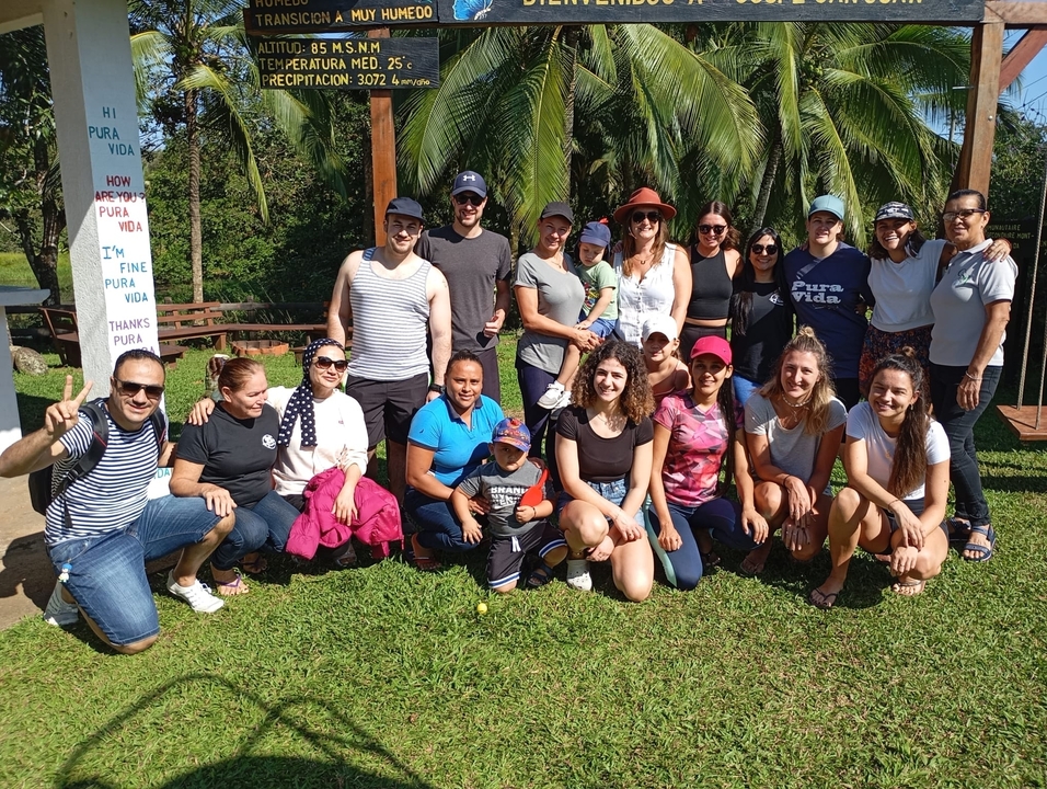 Grand groupe de personnes posant dans une zone herbeuse.
