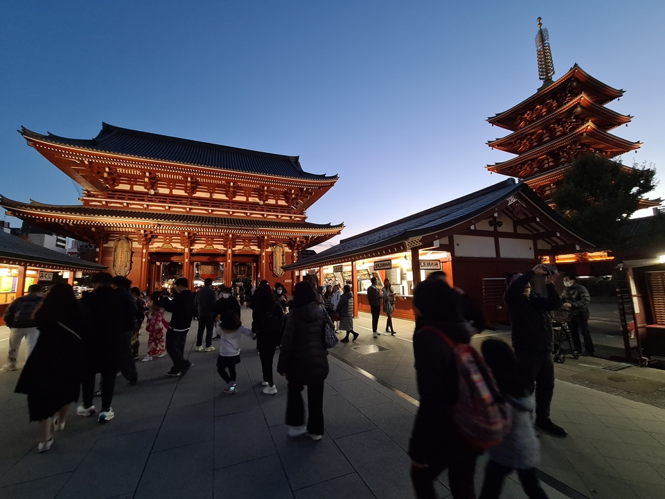 Scène nocturne d'un temple avec des visiteurs en tenue traditionnelle.