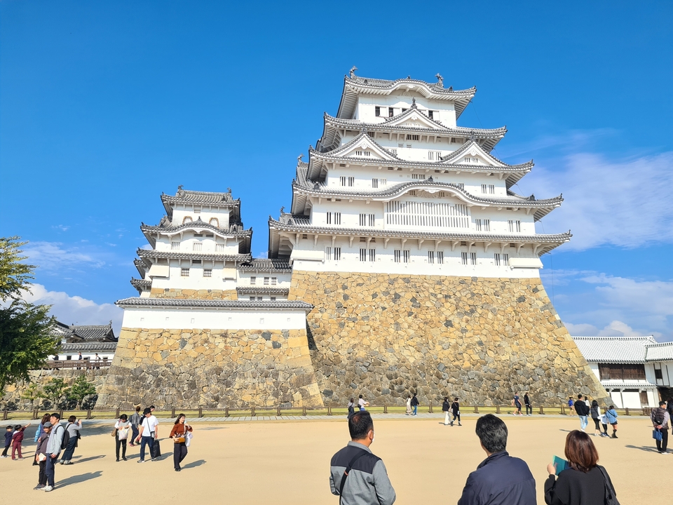 Château de Himeji avec un ciel bleu dégagé et des visiteurs à proximité.