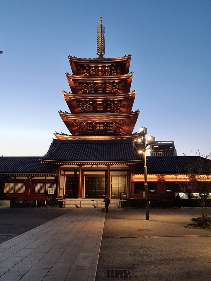 Temple Senso-ji au crépuscule avec des lumières illuminant le bâtiment.