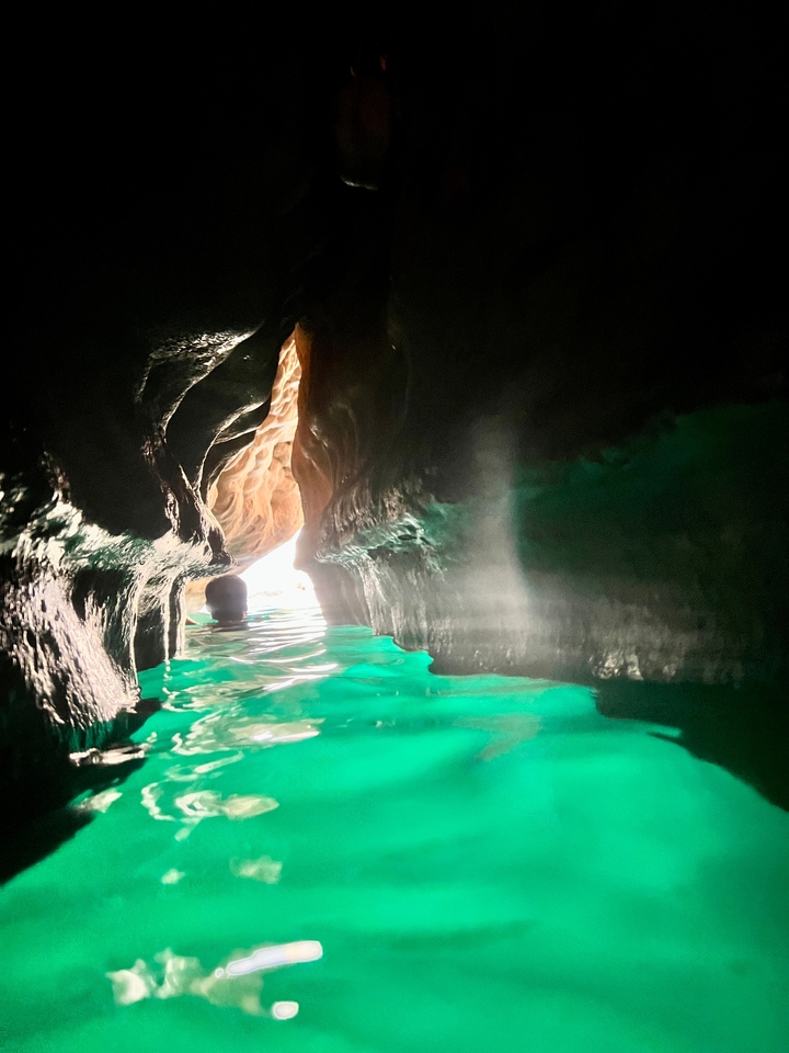 À l'intérieur d'une grotte avec de l'eau turquoise et une personne qui nage.
